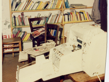 Zerschnittenes Foto einer Druckmaschine im Keller der Umweltbibliothek vor einem Bücherregal.