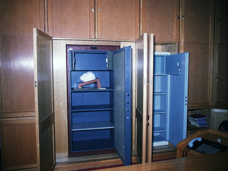 Die Aufnahme zeigt eine Front von Einbauschränken hinter dem ehemaligen Schreibtisch von Erich Mielke, von denen zwei geöffnet sind.