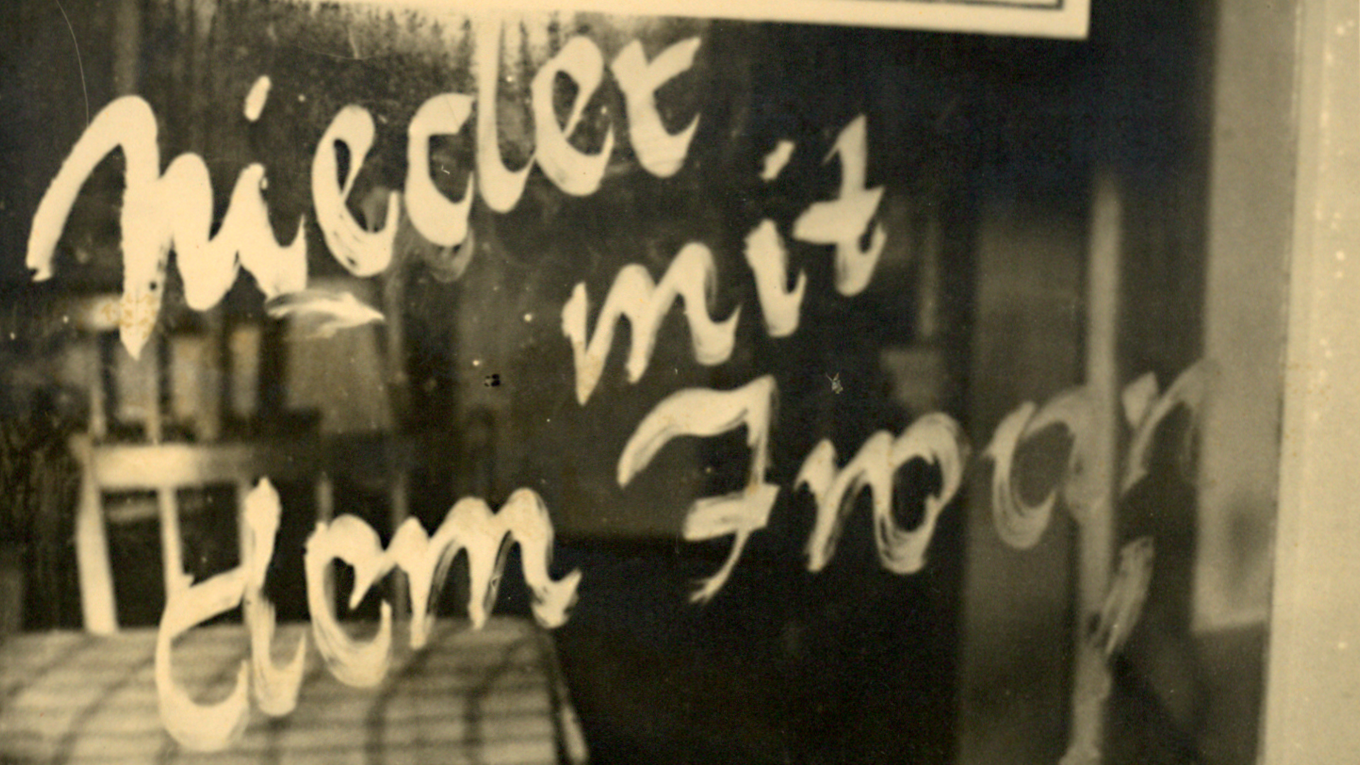 Eine Losung mit dem Schriftzug "Nieder mit dem Iwan" auf einer in der Tür verbauten Fensterscheibe.